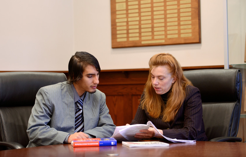 A professor and student examine a textbook together