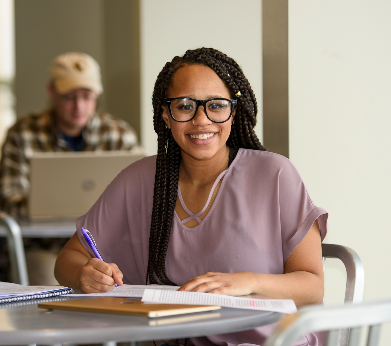 A student smiles for a photo while studying in the Book & Bean