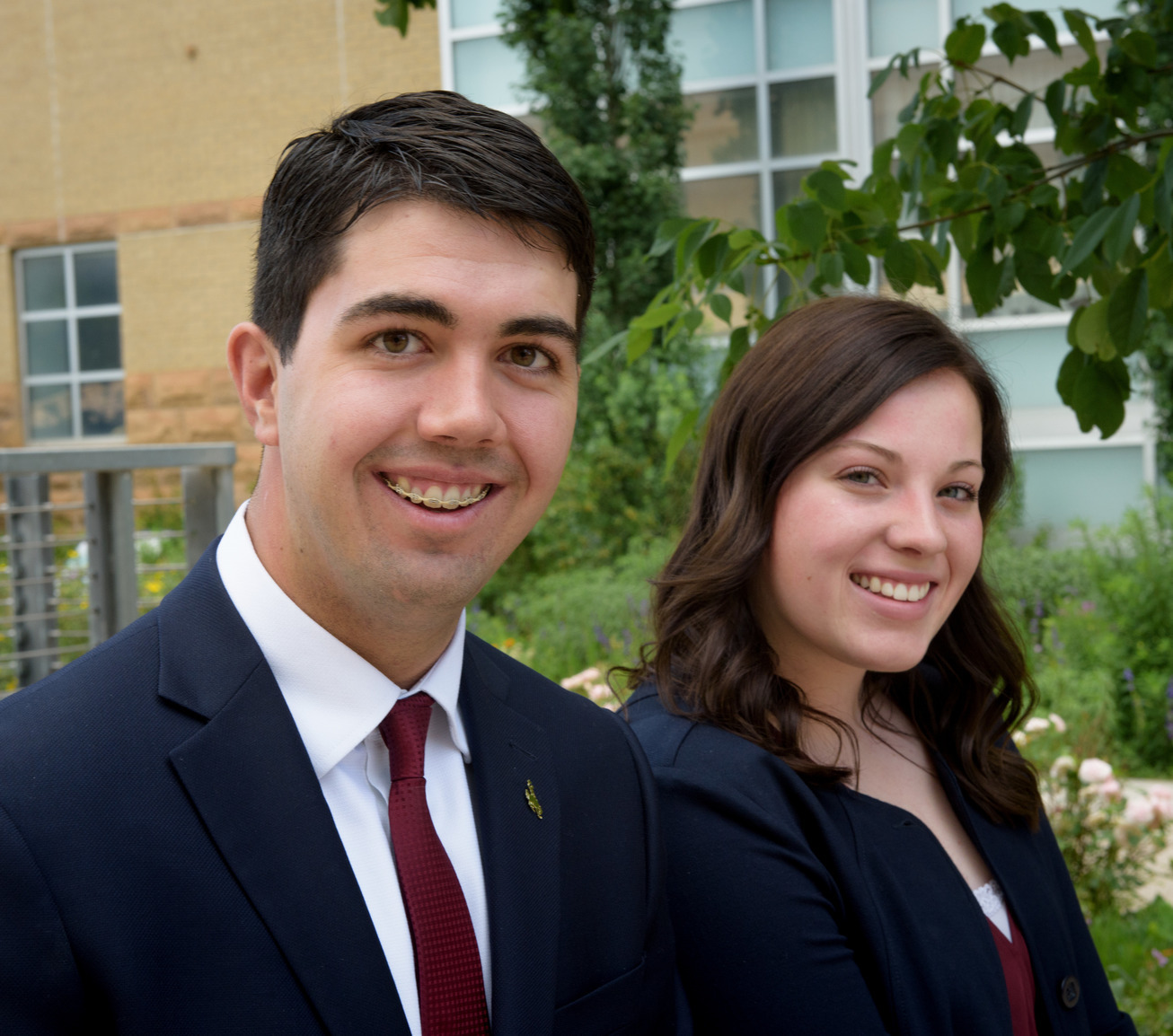Two students in formal business wear smiling for a photo