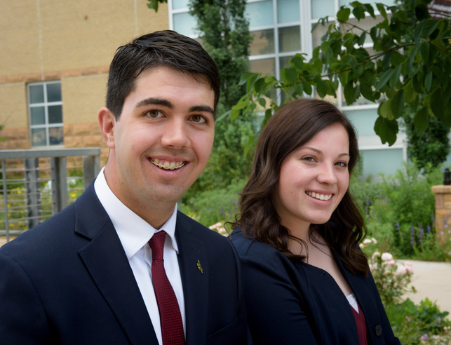 Two students in suits smiling
