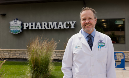 A pharmacy alum stand outside a pharmacy and smiles for a photo