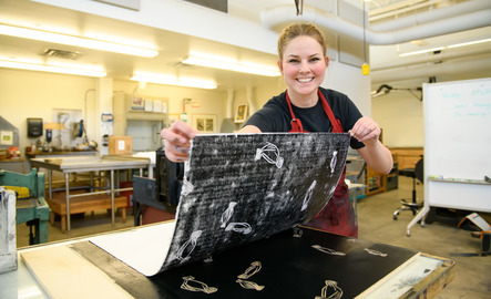 Student smiles while holding their print