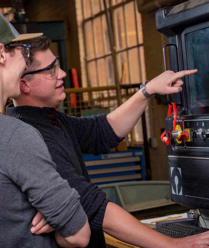 Two students looking at a process control instrument in a lab