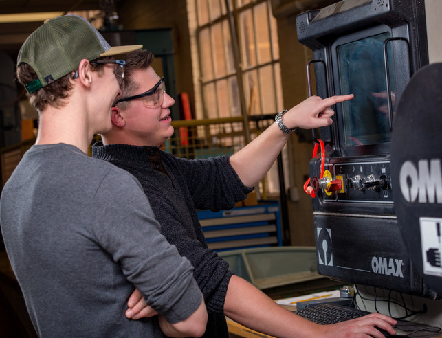 Two students looking at a process control instrument in a lab