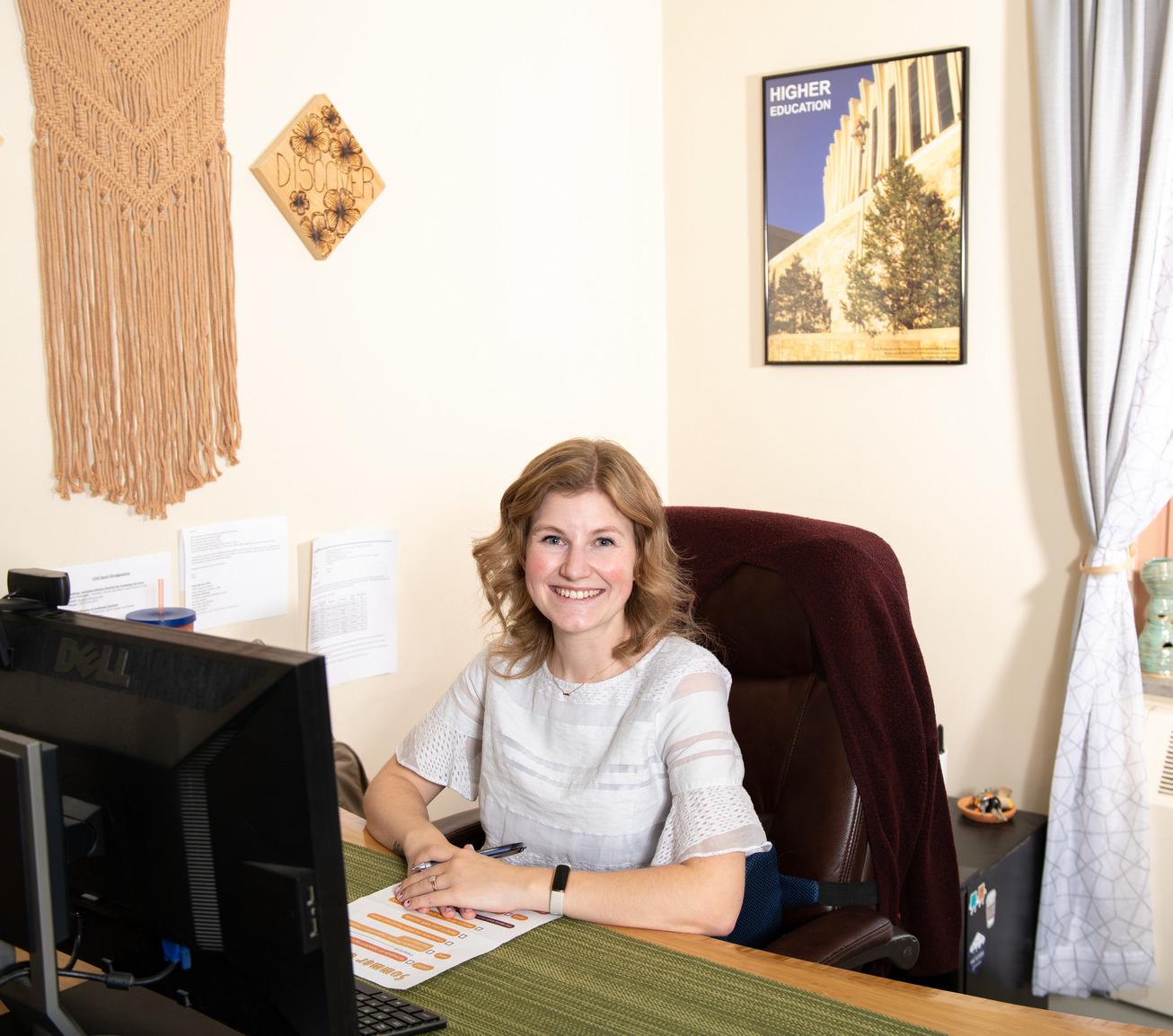 Staff member sitting at desk and smiling for a picture