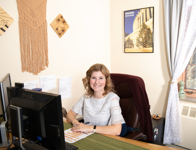 UW staff member sitting at desk and smiling for a picture