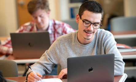 Student writing on a laptop computer