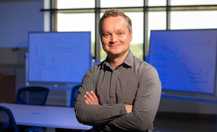 Grad student crosses their arms and smiles