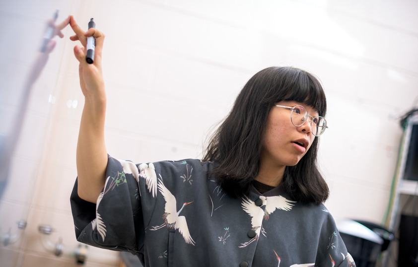 A student points at a white board with a market in their hand