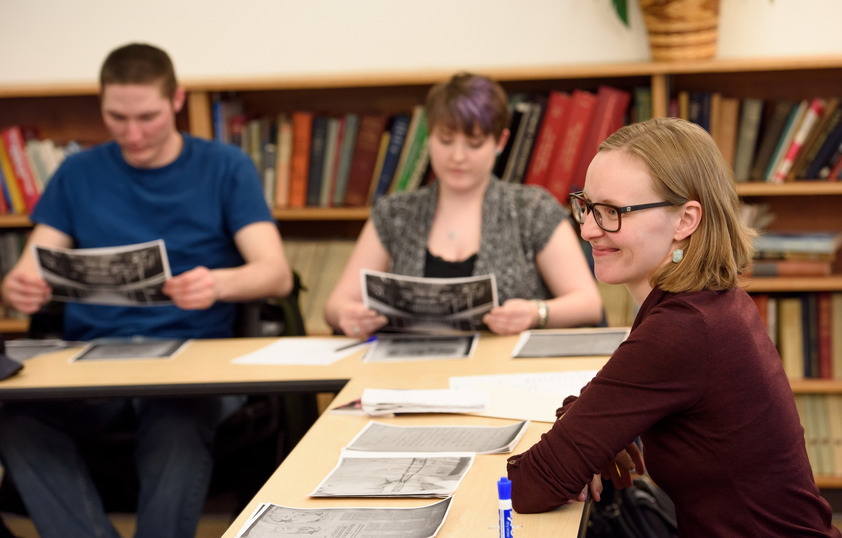 Students and faculty sitting around table looking at photos together