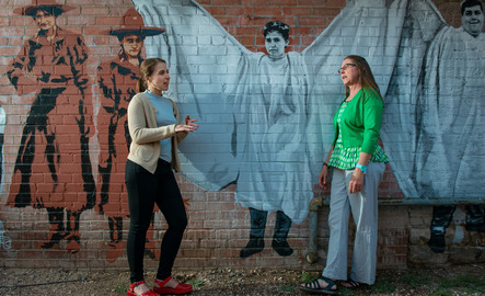 Two people standing in front of Matthew's Angels mural