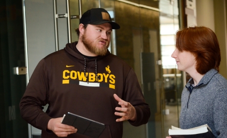A professor and a student talk in a hallway
