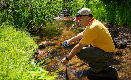 RRE researcher gathering a sample from a water source