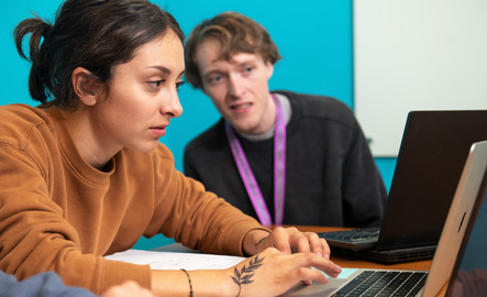 Two students work on laptops