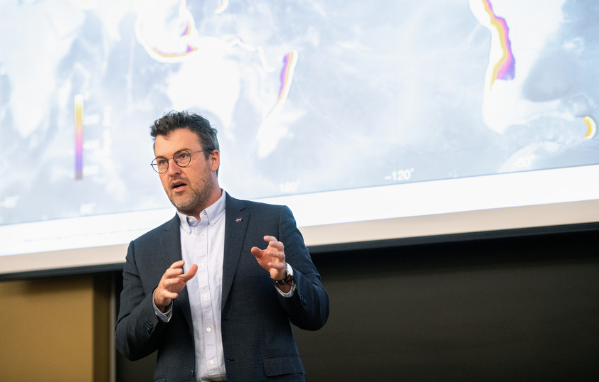 Professor lecturing in front of screen 