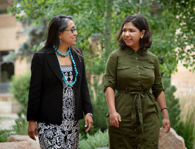 Two graduate students walk on campus