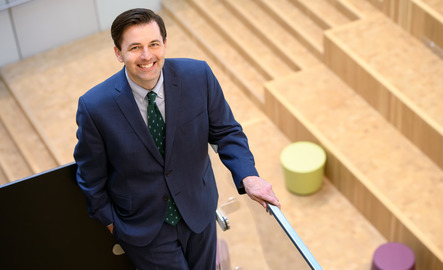 Student wearing a suit smiles for a photo