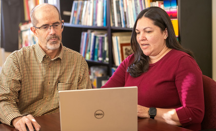Professor and grad studet work on a laptop