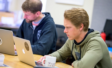 Two students work on laptops