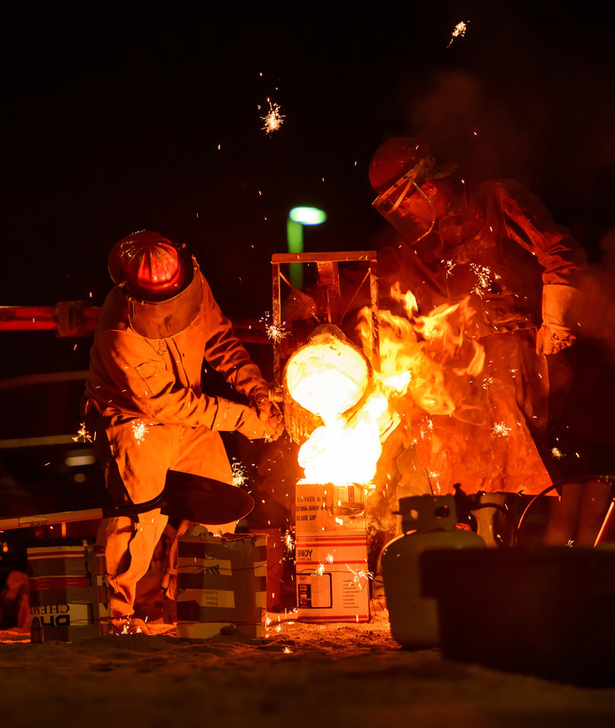 Two sculpture students participating in an iron pour