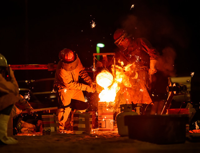 Two sculpture students participating in an iron pour