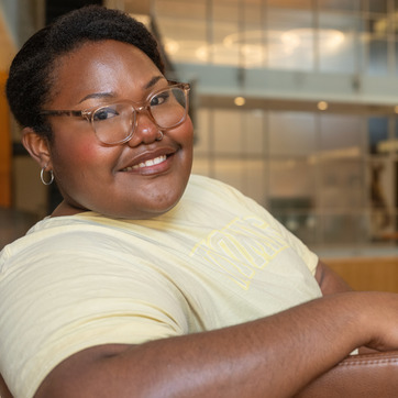 A student smiles for a photo while sitting in a chair