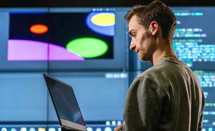 Student stands in front of screen with code on it