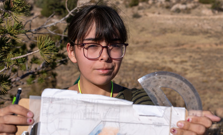 Student holds a clipboard and protractor