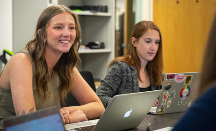 Student smiling with laptop in front of them