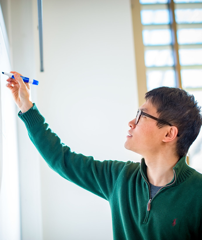 Statistics graduate student writing on a whiteboard