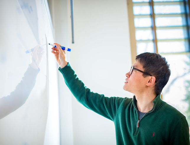 Statistics graduate student writing on a whiteboard