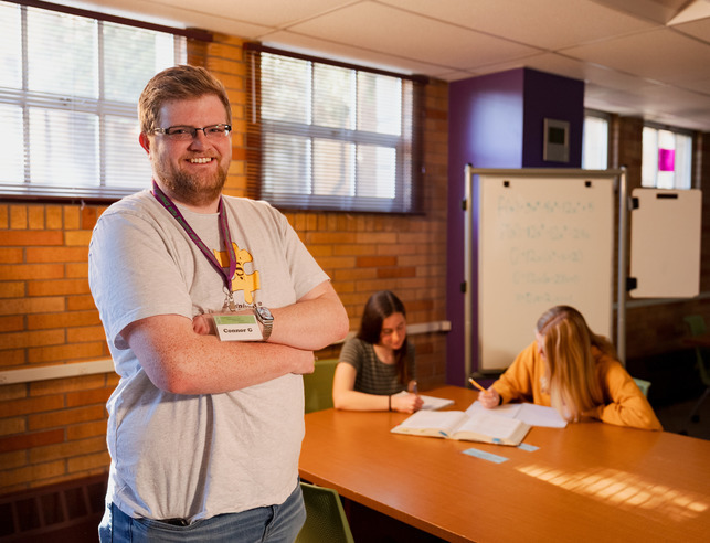 A student smiles for a photo in a tutoring room