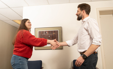 A student and an advisor shake hands