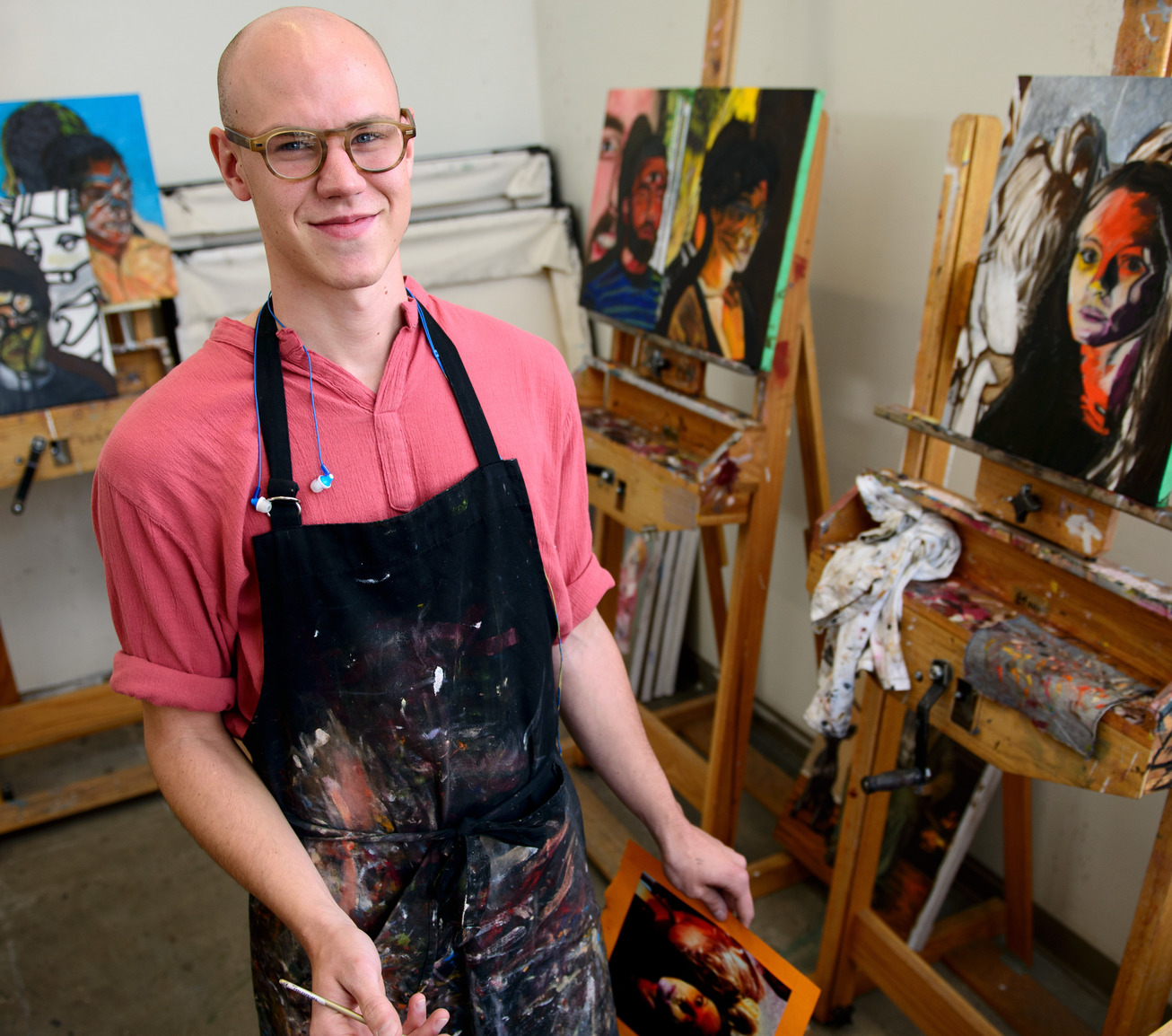 a painter standing near paintings on easels