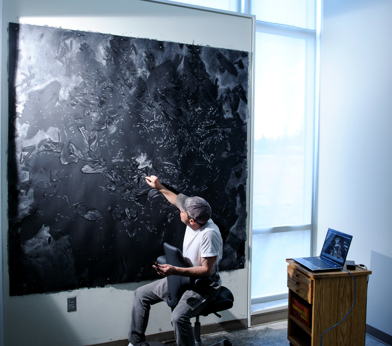an artist works on a large drawing