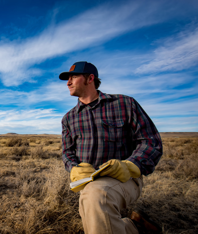 Sustainability researcher holds a pen and notepad in a dry field