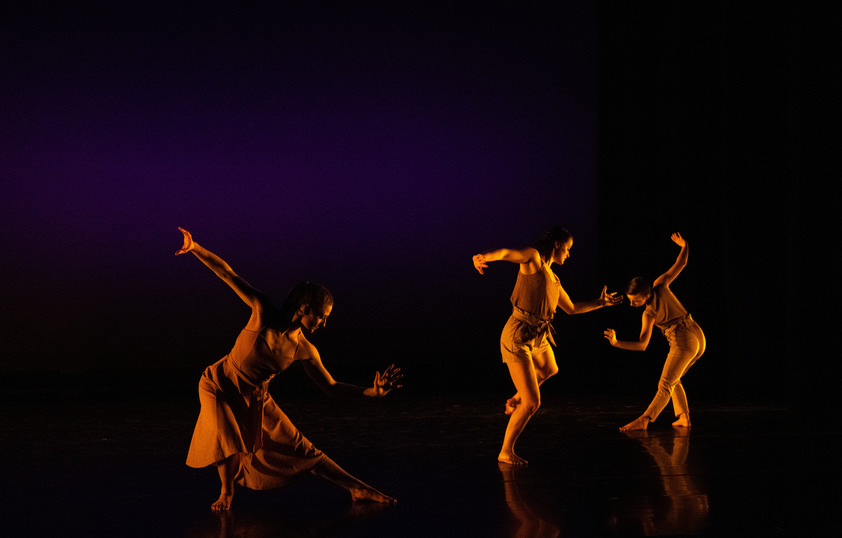 Three students performing on a dimly lit stage