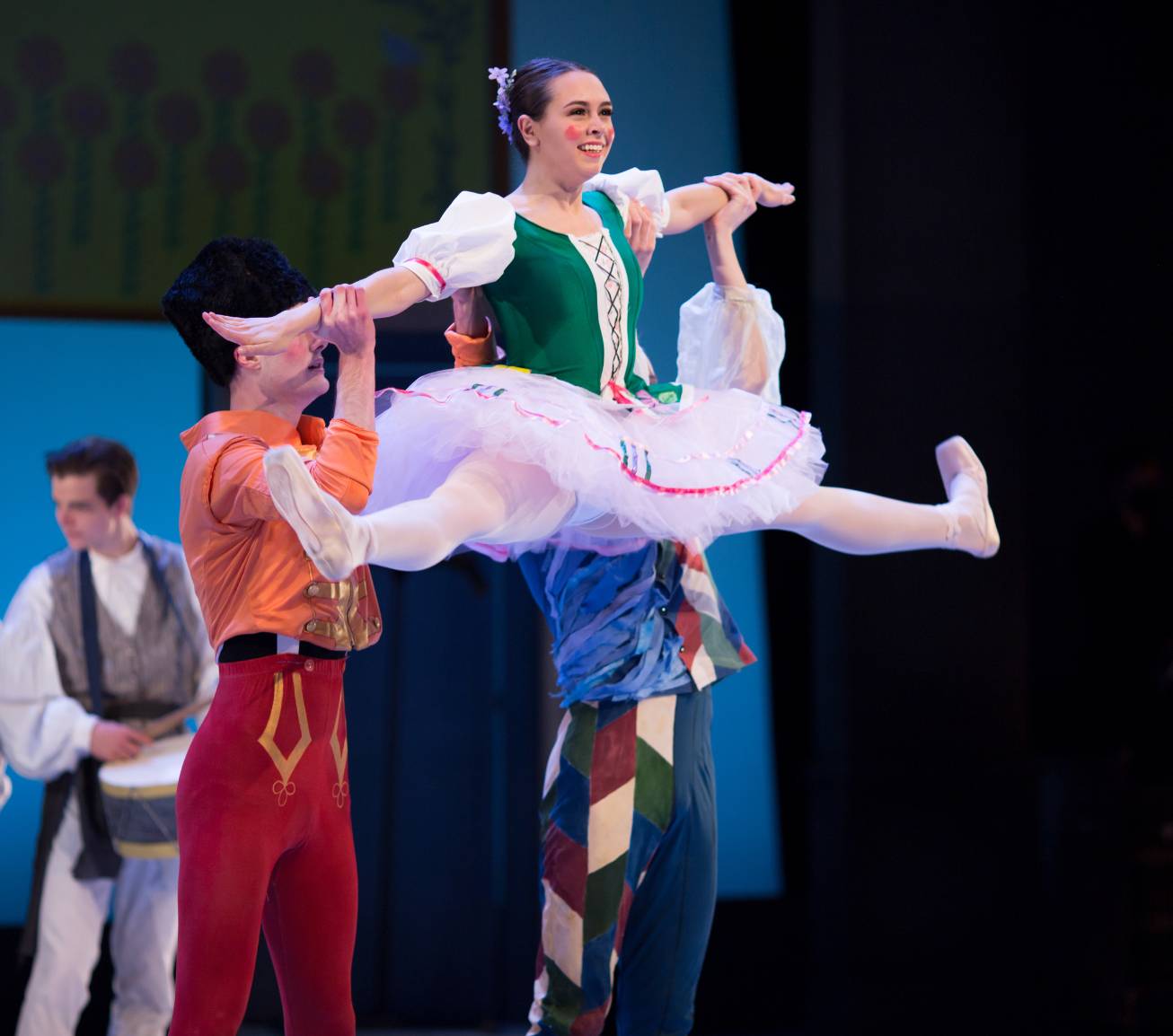 Ballerina being tossed in the air by two other students on stage during performance