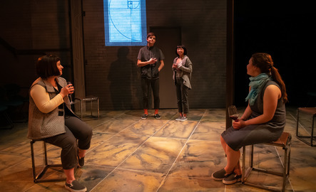 Four students perform a scene on stage