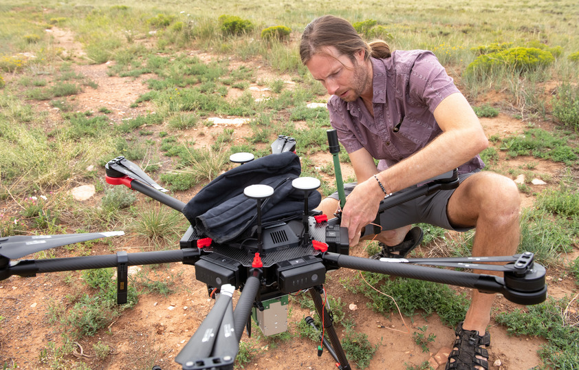 A graduate student performs maintenance on a drone.