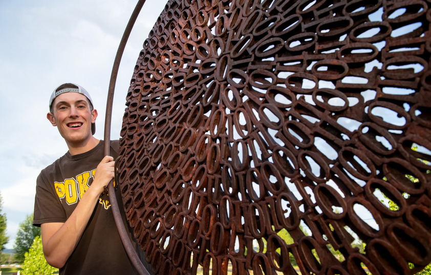 Student next to metal sculpture