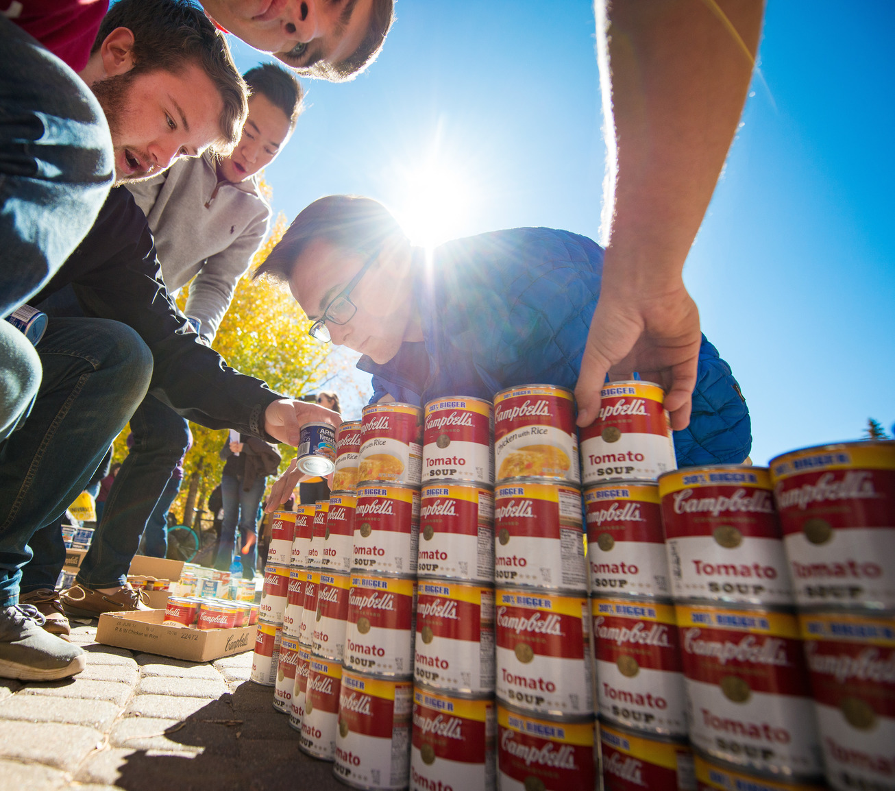 a group of students are stacking Campbell's soup cans