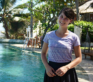 woman standing outside near a pool and tropical plants