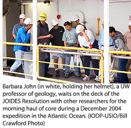 Barbara John (in white, holding her helmet), a UW professor of geology, awaits on deck the JOIDES Resolution with other researchers for the morning haul of core during a December 2004 expedition in  the Atlantic Ocean. 