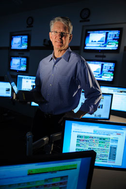 Man standing among lit computer screens