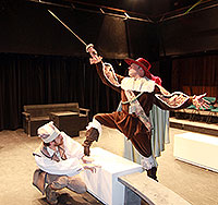 two men in costume - one is crouching and one waves a sword