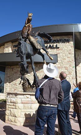 two men looking up at bucking horse statue
