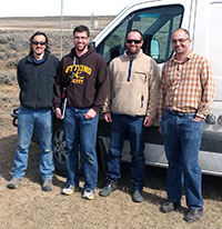 four men standing in front of a van
