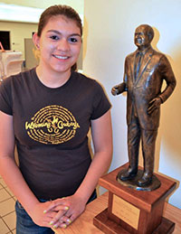 woman standing with small bronze statue of man beside her