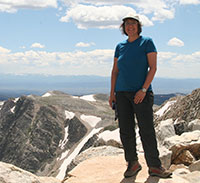 woman standing on a rock with rugged rocky mountain tops in the background